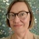 Headshot of Sini Rinne-Kerridge, NCVO Lead Consultant, wearing glasses and smiling in front of a floral wallpaper background.